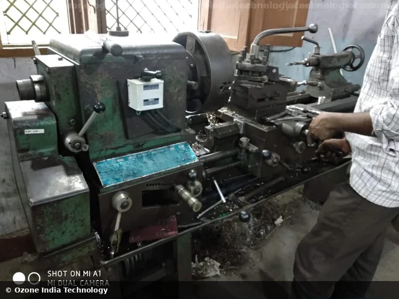 Worker operating a conventional engine lathe for precision turning