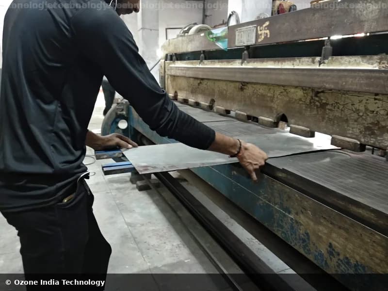 Worker feeding sheet metal into a guillotine shearing machine